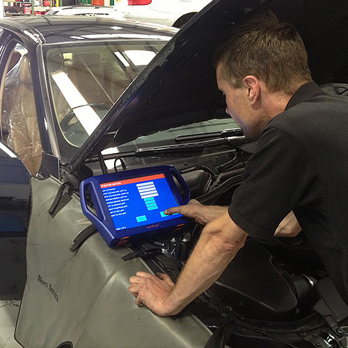 Mechanic with diagnostic machine resetting dashboard computer